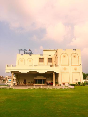a building with a green field in front of it at Hotel Sepal in Bathinda