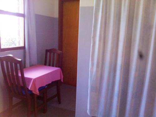a dining room with a pink table and chairs at Retreat Guesthouse Kitende in Entebbe