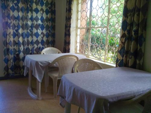 a room with two tables and chairs and a window at Retreat Guesthouse Kitende in Entebbe