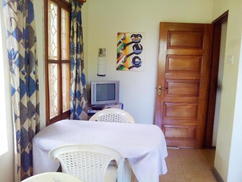 a room with a table and two chairs and a television at Retreat Guesthouse Kitende in Entebbe