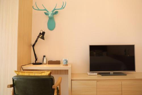 a living room with a tv and a chair and a lamp at Yumi Apartment Lida Plaza Branch in Guangzhou