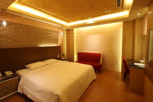 a bedroom with a white bed and a red chair at R7 Hotel in Kaohsiung