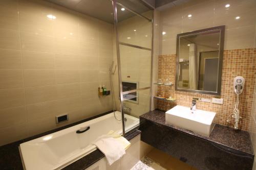 a bathroom with a tub and a sink and a bath tub at R7 Hotel in Kaohsiung