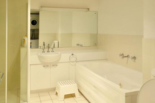 ein weißes Badezimmer mit einer Badewanne und einem Waschbecken in der Unterkunft Kingston Comfy Apartment in Kingston 