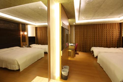 a hotel room with three beds and a mirror at R7 Hotel in Kaohsiung