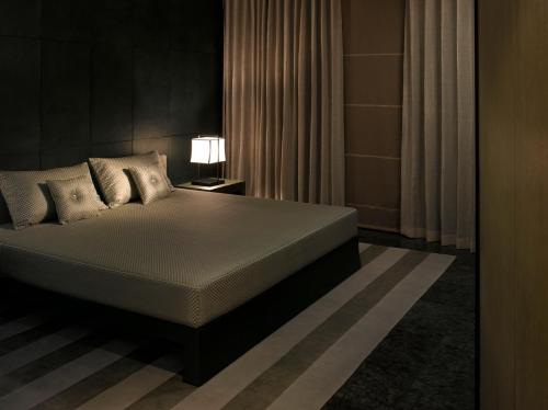 een slaapkamer met een bed en een lamp en gordijnen bij Armani Hotel Dubai, Burj Khalifa in Dubai