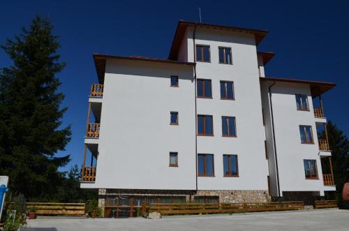 a large white building with a tree in the background at EldoSport Hotel in Dospat