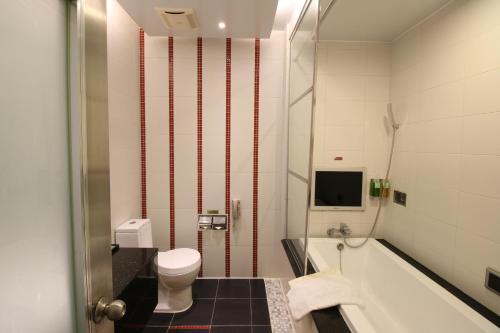 a bathroom with a tub and a toilet and a sink at R7 Hotel in Kaohsiung