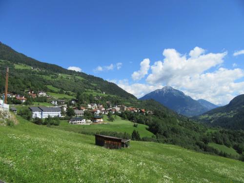 a green hillside with a small town in a valley at Neuner Charlotte Preise inclusive Sommercard in Wenns