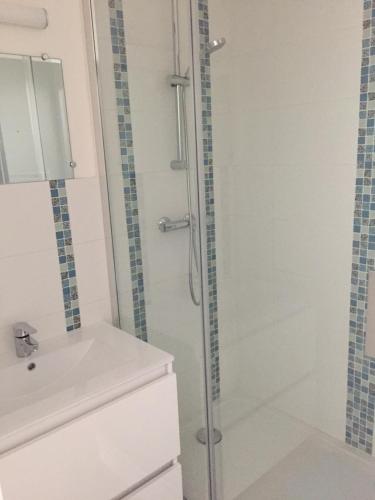 a white bathroom with a shower and a sink at La Houle in Cancale