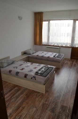 two beds in a room with wooden floors at EldoSport Hotel in Dospat