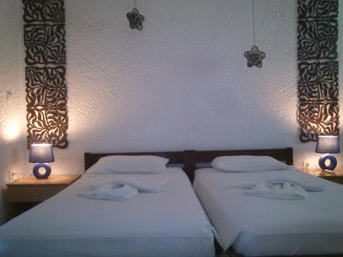 two twin beds in a bedroom with two lamps at Kiotari Beach Apartments in Kiotari