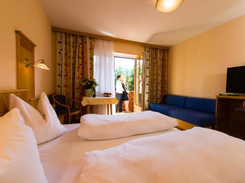 a hotel room with two beds and a woman looking out the window at Gasthof Hotel Schmied in Arnfels