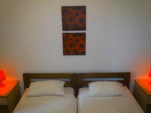 two beds in a room with two lamps and a painting on the wall at Kiotari Beach Apartments in Kiotari