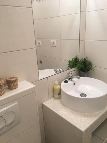 W białej łazience znajduje się umywalka i lustro. w obiekcie Apartments Lucia w mieście Pag