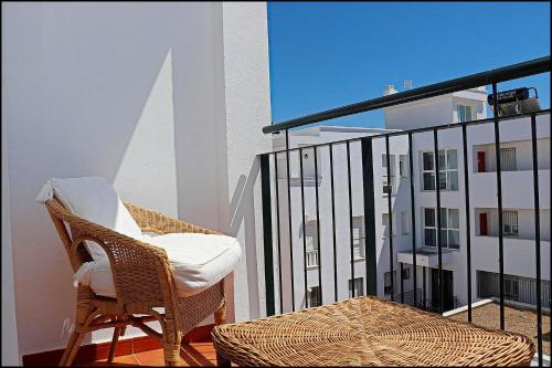 コニル・デ・ラ・フロンテーラにあるApartamento Conil con terrazaの椅子、建物の景色を望むバルコニー