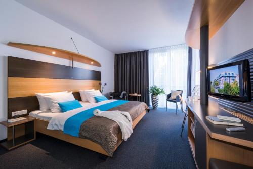 a hotel room with a bed and a flat screen tv at SEEhotel Friedrichshafen in Friedrichshafen