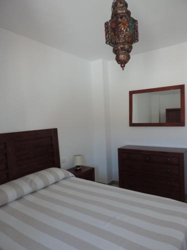 1 dormitorio con cama, espejo y lámpara de araña en Apartamento Barbancho, en Casar de Cáceres