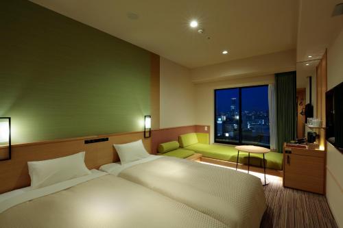 a hotel room with a bed and a window at Candeo Hotels Osaka Namba in Osaka