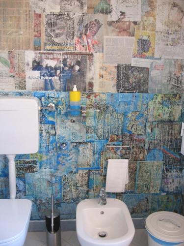 a bathroom with a toilet and a sink and a newspaper wall at Stanza d'artista in Genova