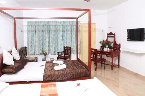 a bedroom with a bed and a desk and a table at Meya Beach Walk Hotel in Mahabalipuram
