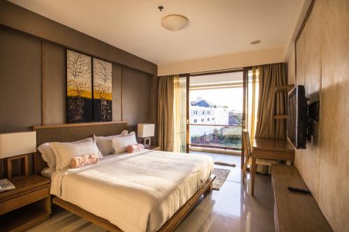 Un dormitorio con una cama grande y un televisor. en Kuta Reef Apartments, en Kuta