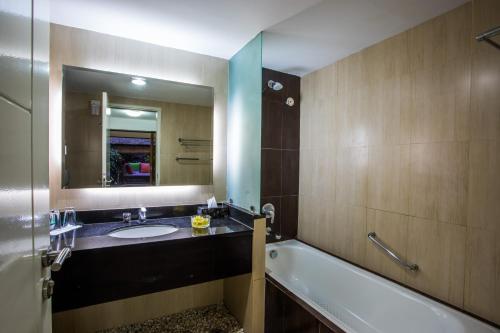 Un baño con lavabo, bañera y espejo. en Kuta Reef Apartments, en Kuta