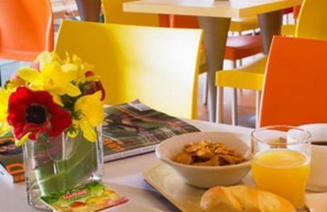 einen Tisch mit einer Vase Blumen und einer Schüssel Essen in der Unterkunft Première Classe Rouen Nord - Bois Guillaume in Bois-Guillaume