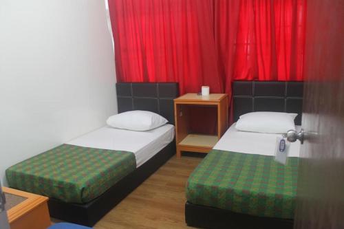 a small room with two beds and red curtains at Georgetown Heritage Motel in George Town