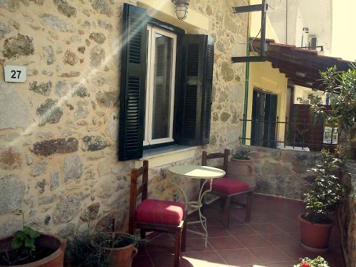 a patio with two chairs and a table and a window at Hariklia Rent Rooms in Zarós