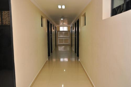 a long hallway with white walls and floors and doors at Hotel Rajam in Kanyakumari