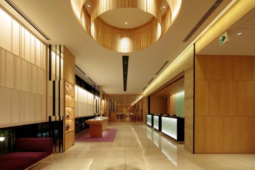 a lobby with a large ceiling with a large light fixture at Candeo Hotels Osaka Namba in Osaka