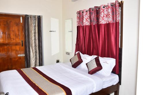 a bedroom with a bed with a red curtain at Barnabas Homestay in Thanjāvūr