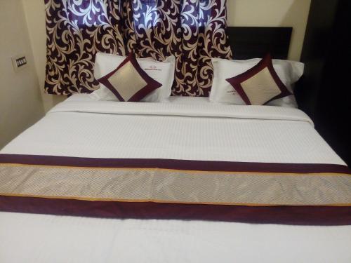 a bed with white sheets and pillows in a room at Barnabas Homestay in Thanjāvūr