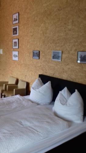 a bed with white pillows and pictures on the wall at Historisches Hotel Wildeshauser Bahnhof in Wildeshausen