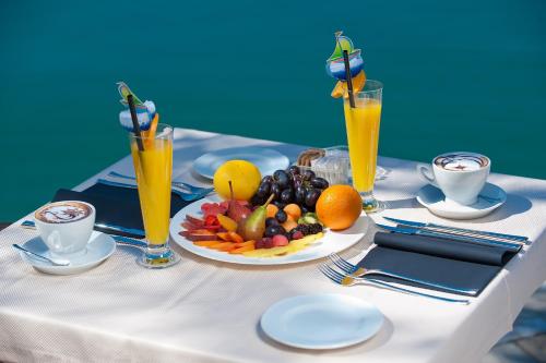 a table with a plate of fruit and orange juice at Hotel Forza Mare in Kotor