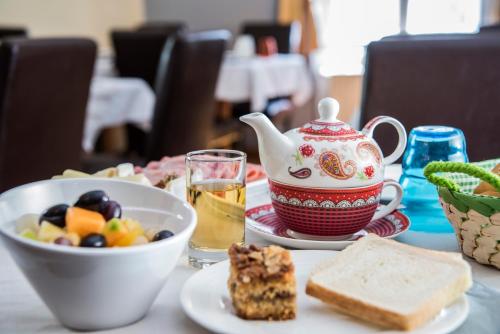 a table with a tea pot and a bowl of food at Stadthotel Kramer in Villach