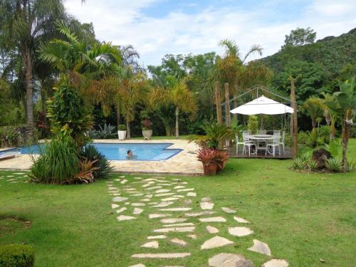 a backyard with a swimming pool with a table and an umbrella at Chacara de Cinema da Montanha in Itariri