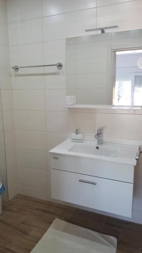 a white bathroom with a sink and a mirror at Apartments Nogic in Peroj