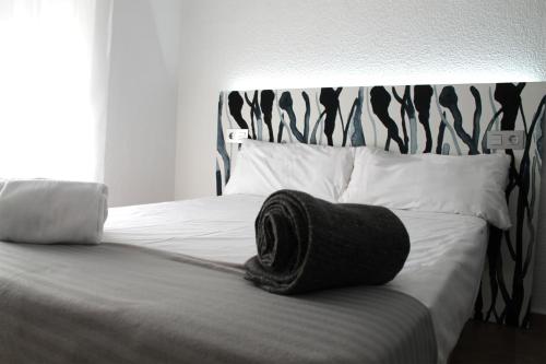 a bed with a black towel sitting on top of it at Alevia in Salamanca