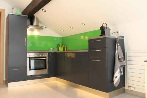 a kitchen with black cabinets and a green wall at Haus Dorf 7 in Saas-Grund