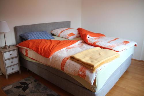 ライプツィヒにあるApartment am Fluss/Parkのベッド(オレンジと白の掛け布団、枕付)