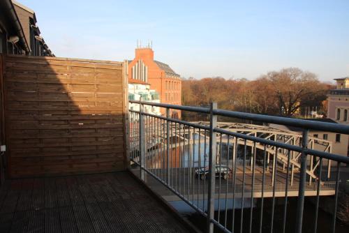 un balcón con una valla de madera y un edificio en Apartment am Fluss/Park en Leipzig