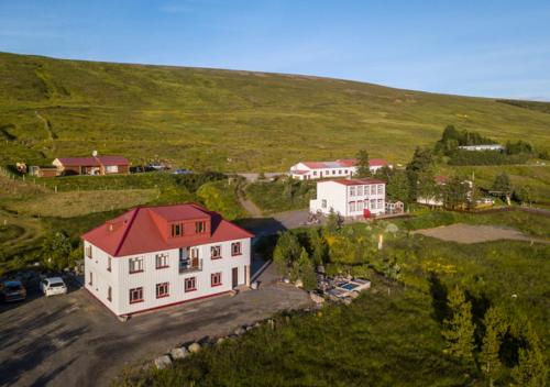 a large white house with a red roof on a hill at Guesthouse Storu-Laugar in Laugar