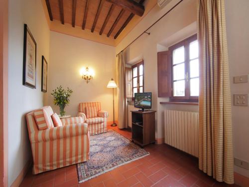 a living room with two chairs and a television at Relais Vignale & Spa in Radda in Chianti