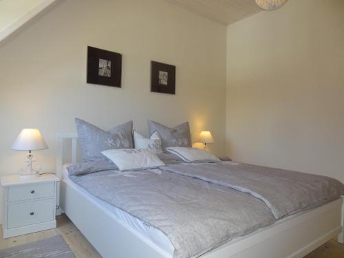 a white bedroom with a large bed with two pictures on the wall at Landliebe in Hasselberg