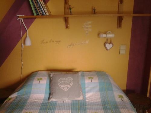 a bedroom with a bed with a pillow on it at Chez Catherine - Chaumière Normande in Theuville-aux-Maillots