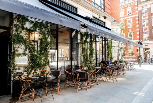 فندق ذا ماريليبون  في لندن: مجموعة طاولات وكراسي خارج المطعم