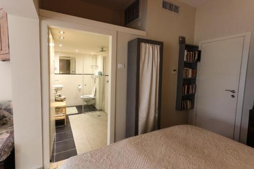 1 dormitorio con puerta que conduce a un baño en Krivine B&B, en Midreshet Ben Gurion
