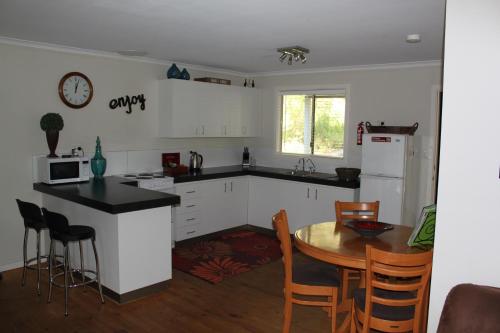 cocina con armarios blancos, mesa y sillas en Francisca's Cottage, en Denmark